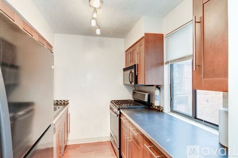 A kitchen with wooden cabinets and a stainless steel refrigerator.