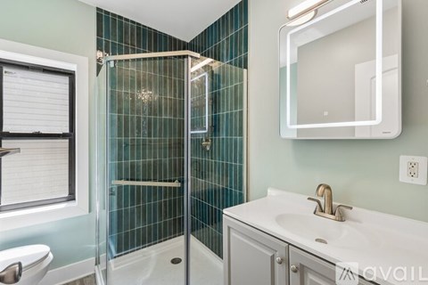 A bathroom with a white sink and a glass shower stall.
