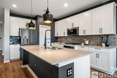 A modern kitchen with white cabinets and a black refrigerator.