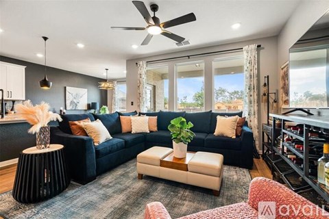 A living room with a dark blue sofa and a fan on the ceiling.
