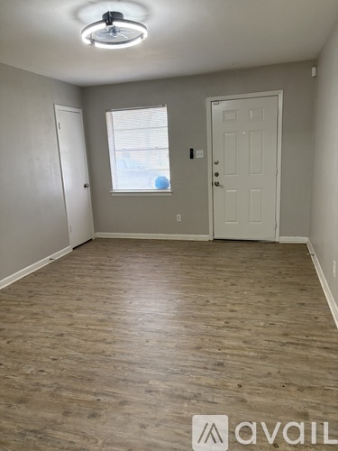 A room with wooden flooring and a window with blinds.