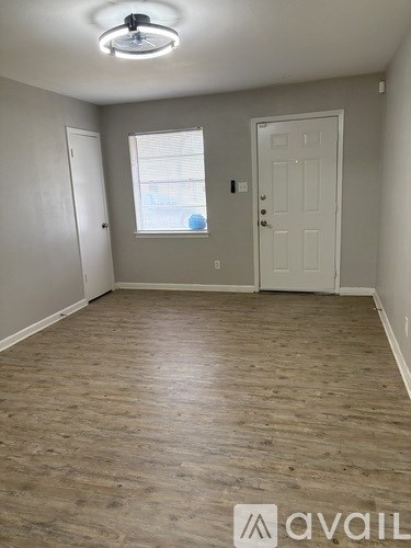 A room with wooden flooring and a window with blinds.
