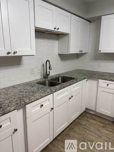 A kitchen with white cabinets and a granite countertop.