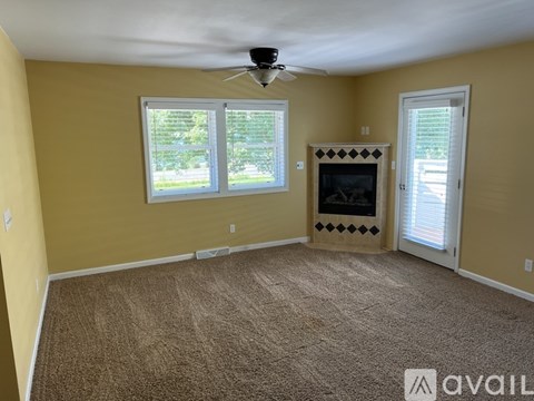 A living room with a fireplace and a ceiling fan.