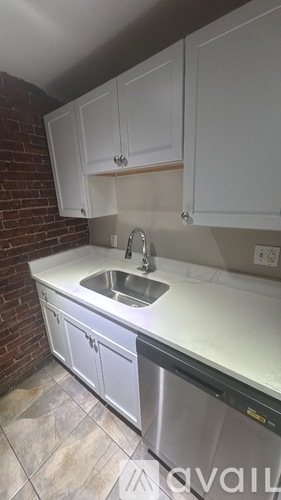 A kitchen with white cabinets and a brick wall.