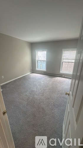A room with a carpeted floor and two windows.