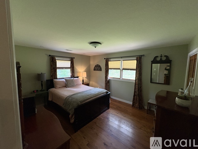 A bedroom with a large bed and wooden floors.