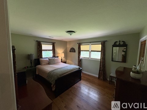 A bedroom with a large bed and wooden floors.