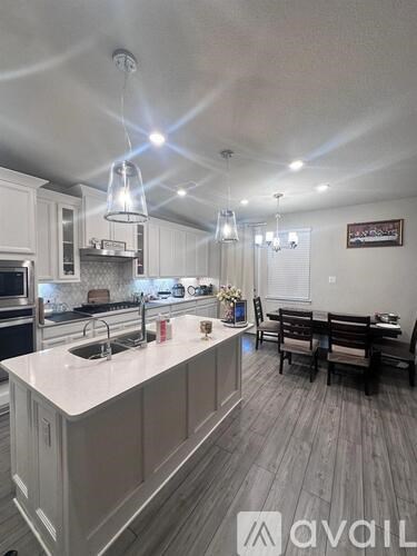 A kitchen with a white countertop and wooden flooring.