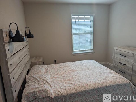 A bedroom with a bed, dresser, and window.