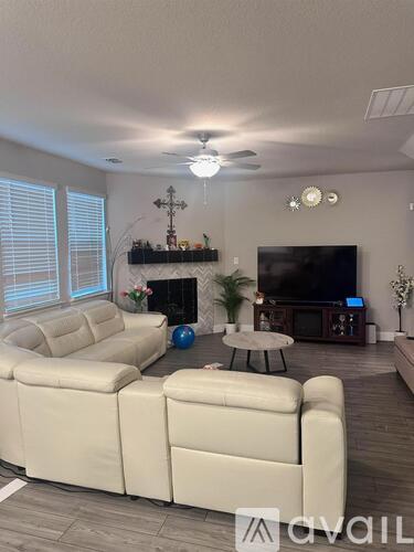 A living room with a white sofa set and a television.
