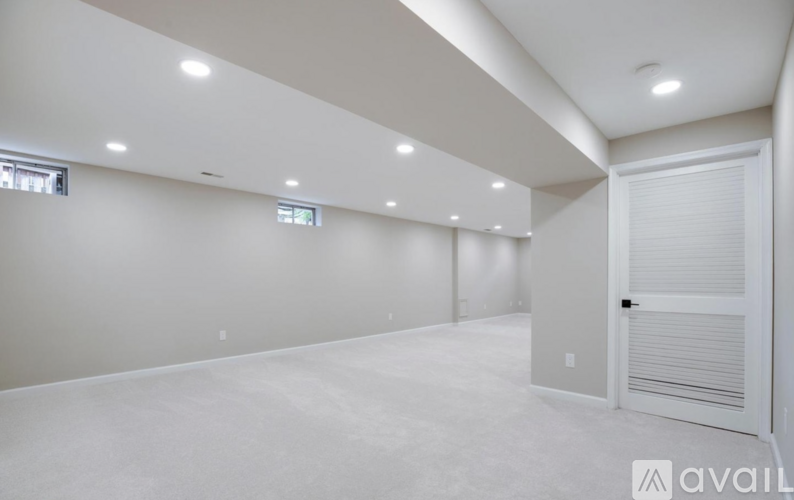 A spacious room with white walls and carpeted floor.