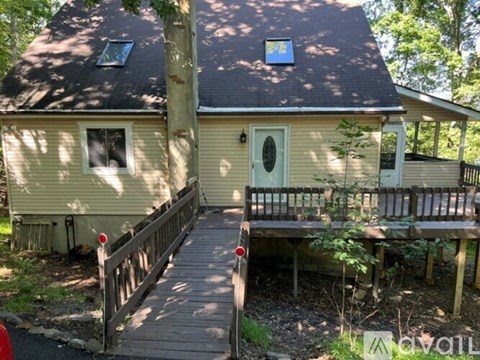 A house with a deck and a tree in front.