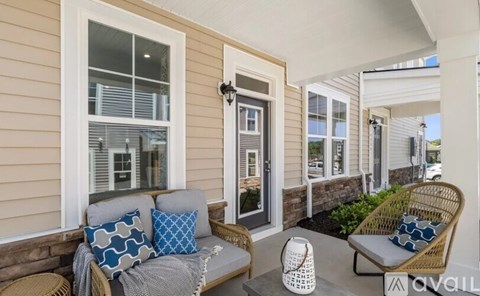 A patio with a couch, pillows, and a chair.