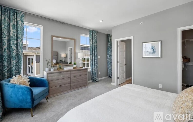 A bedroom with a blue chair and a large bed.