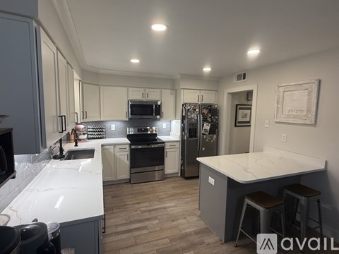 A kitchen with a white countertop and a refrigerator with a picture on the wall.