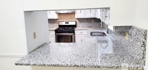 A kitchen with granite countertops and a stove top oven.
