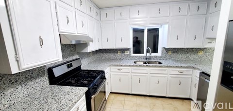 A kitchen with white cabinets and granite countertops.