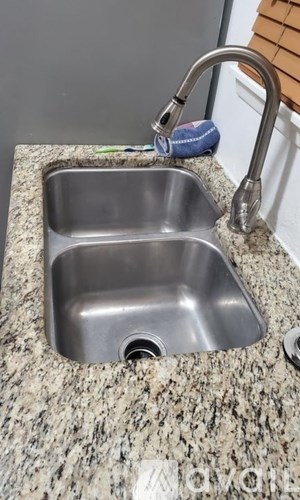 A stainless steel kitchen sink with a granite countertop.