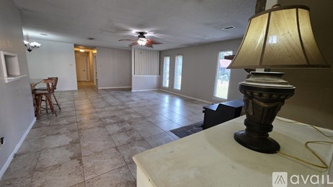 A living room with a lamp on a table and a ceiling fan.