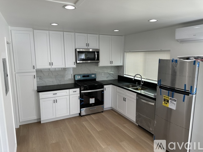A kitchen with white cabinets and a stainless steel refrigerator.