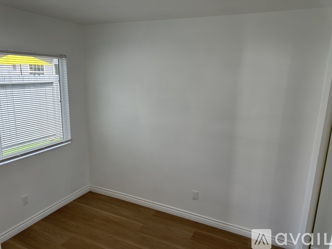 A room with a window and wooden flooring.