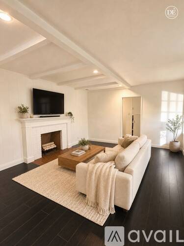 A living room with a white couch, a fireplace, and a flat screen TV mounted on the wall.