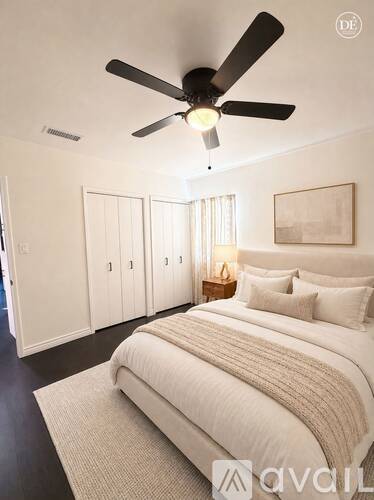 A bedroom with a large bed and a ceiling fan.