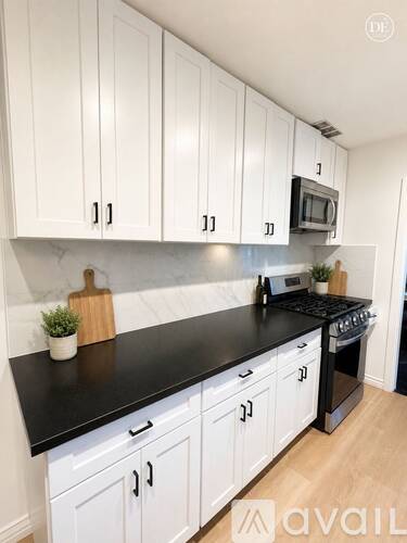 A kitchen with white cabinets and black countertops.