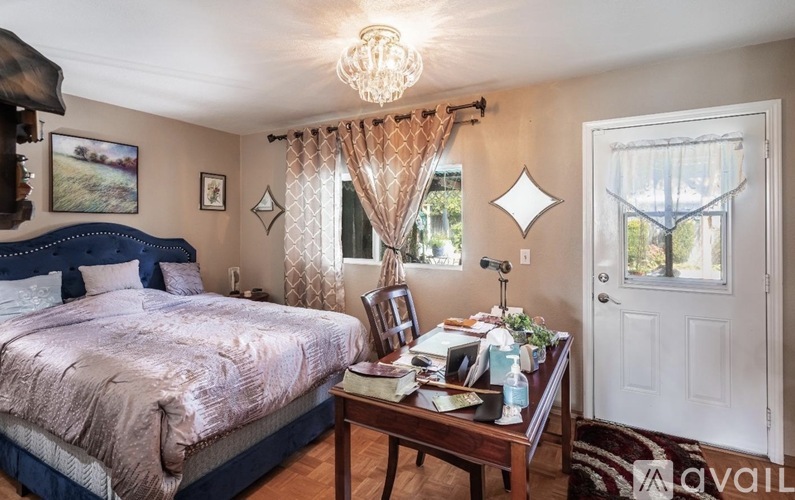 A bedroom with a bed, nightstand, and a table with a lamp on it.