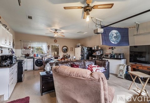 A living room with a couch and a fan.