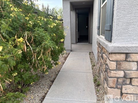 A concrete pathway leads to a door in a house.