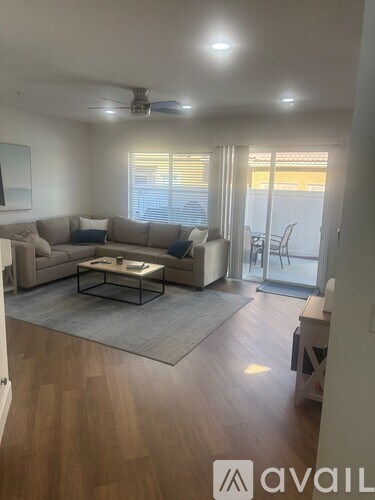 A living room with a couch, a coffee table, and a ceiling fan.