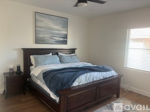A bedroom with a bed, nightstand, and a painting on the wall.