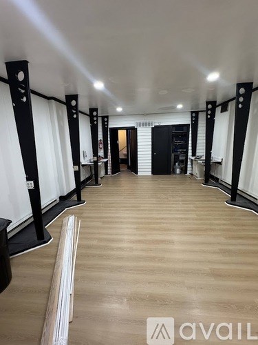 A long hallway with black poles on the sides and a wooden floor.