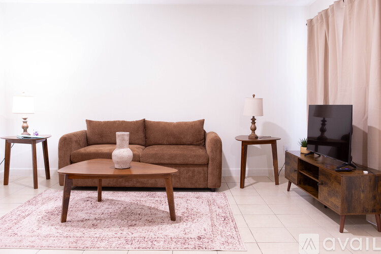 A living room with a brown couch, a coffee table, and a TV.