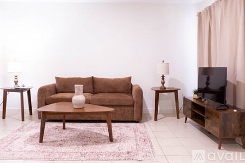 A living room with a brown couch, a coffee table, and a TV.