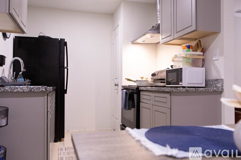 A kitchen with a black fridge and a white microwave on the counter.