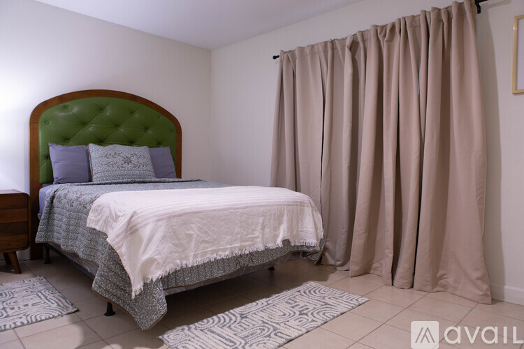 A bedroom with a large bed and a green headboard.