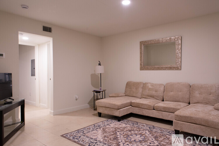 A living room with a beige sofa and a mirror on the wall.