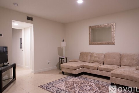 A living room with a beige sofa and a mirror on the wall.