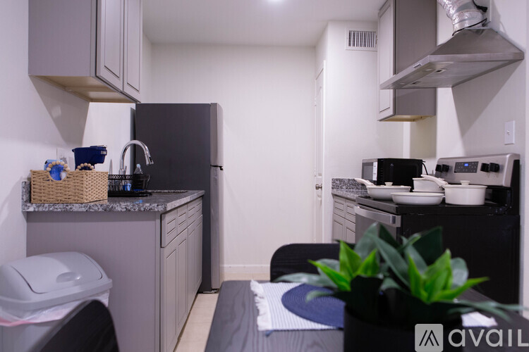 A kitchen with a black fridge and a black stove top.