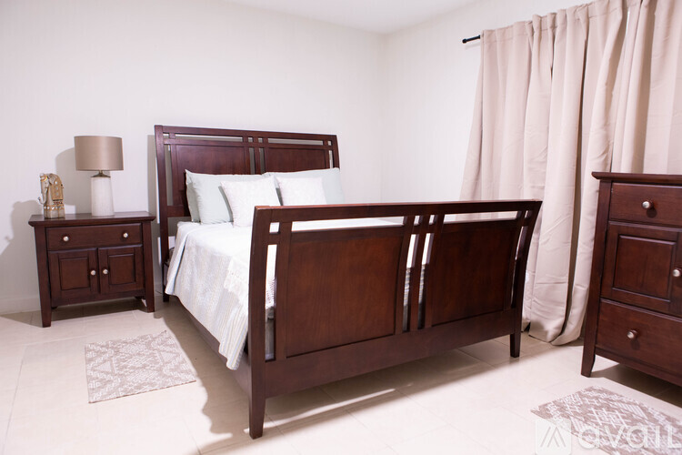 A bedroom with a bed, nightstand, and dresser.