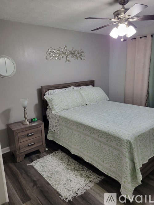 A bedroom with a bed, nightstand, and a ceiling fan.
