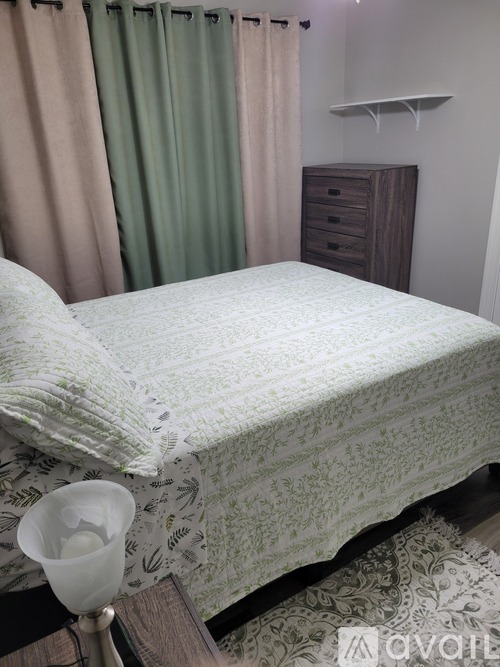 A bed with a white comforter and a lamp on a side table.