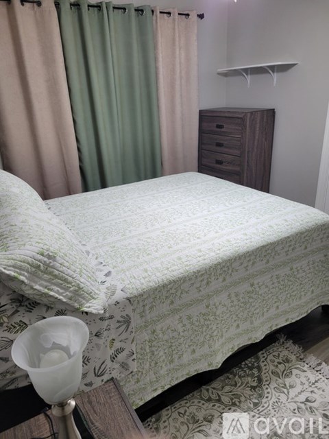 A bed with a white comforter and a lamp on a side table.