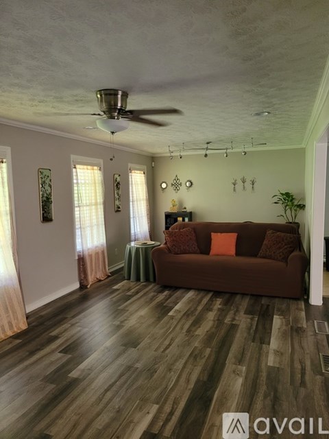 A living room with a brown couch and a ceiling fan.