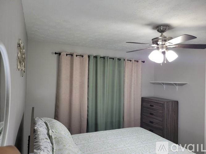 A bedroom with a bed, dresser, and a ceiling fan.