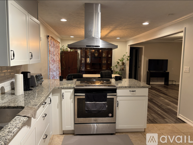A modern kitchen with a stainless steel range hood and white cabinets.