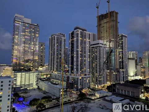 A cityscape at dusk with a building under construction prominently in the foreground.